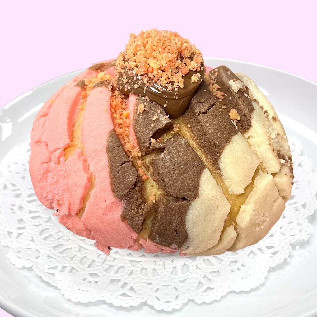 A concha topped in pink, chocolate and vanilla stripes