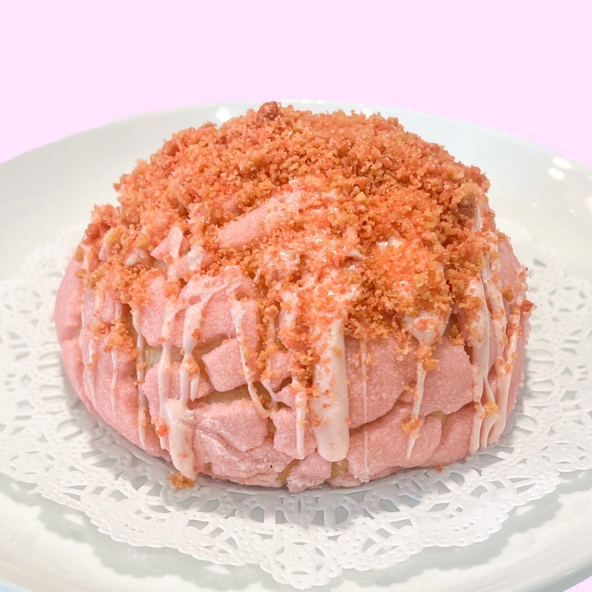 A pink strawberry crunch concha with a crackled shell topping