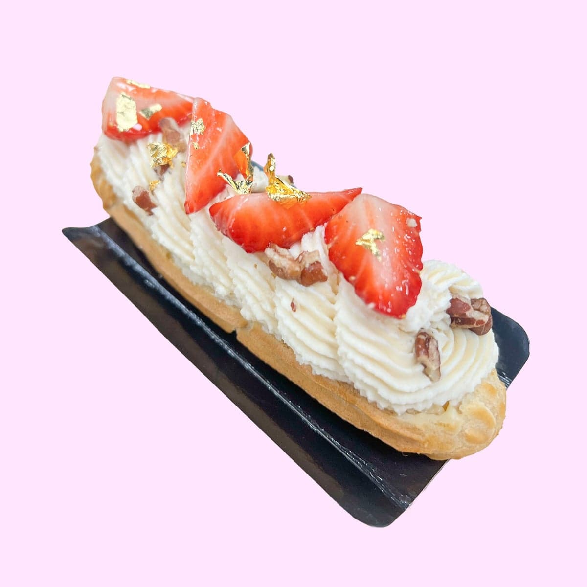 A dulce de leche eclair piped with cream and topped with fresh strawberries