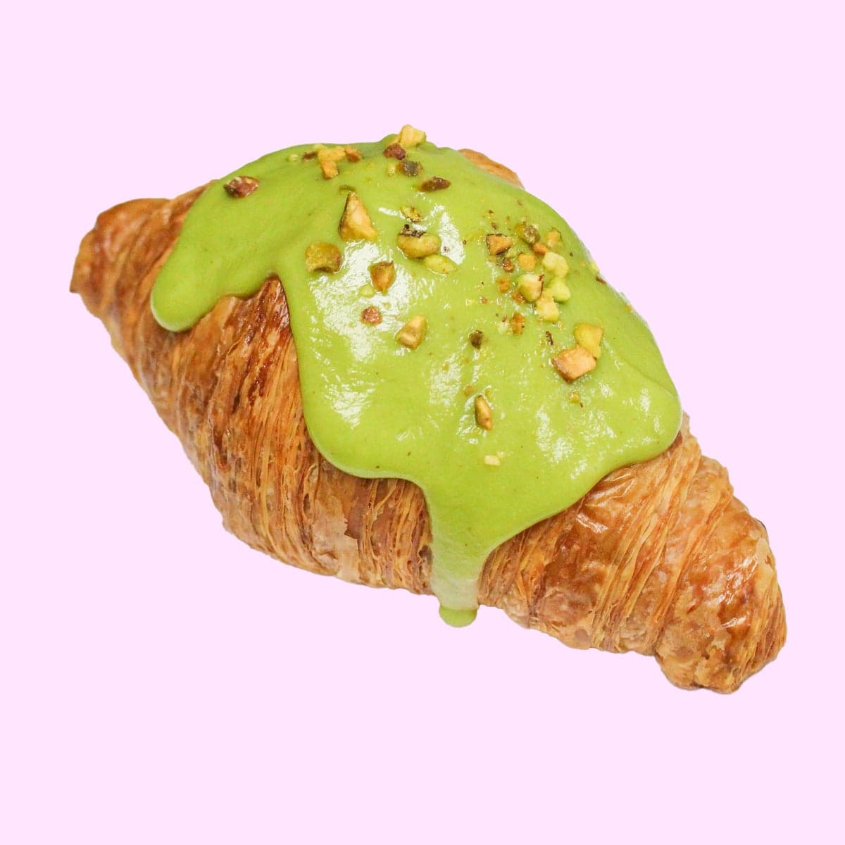 A croissant glazed in green pistachio and scattered with crushed pistachios