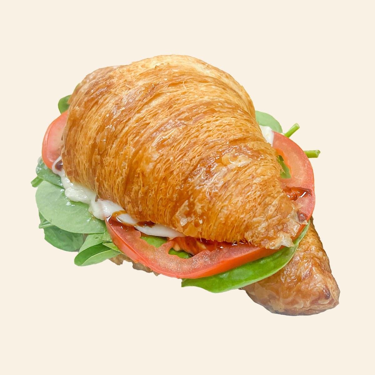 A croissant sandwich with pesto, tomato, mozzarella and spinach